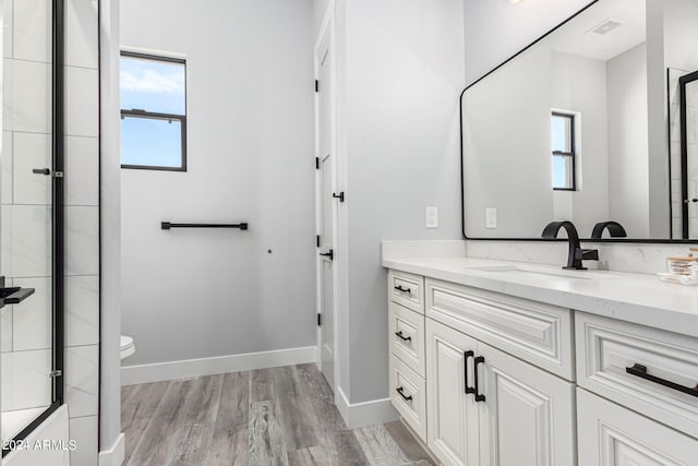 bathroom with vanity, toilet, wood-type flooring, and walk in shower