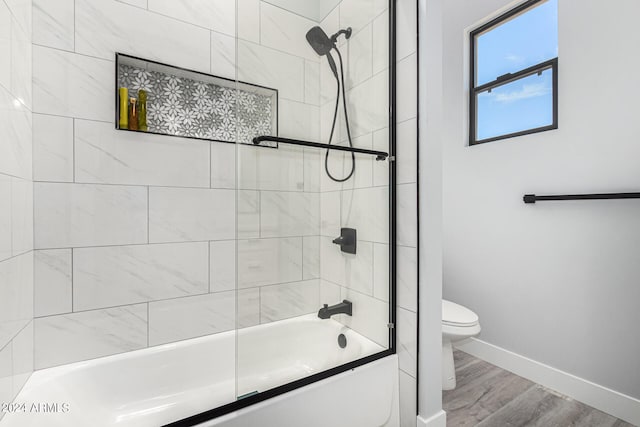 bathroom featuring tiled shower / bath combo, hardwood / wood-style flooring, and toilet