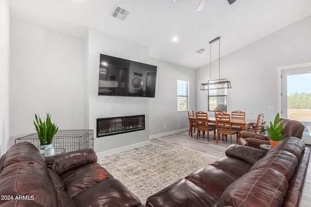 living room with hardwood / wood-style floors, ceiling fan with notable chandelier, and vaulted ceiling