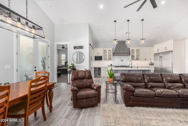 living room with sink, high vaulted ceiling, light wood-type flooring, and ceiling fan