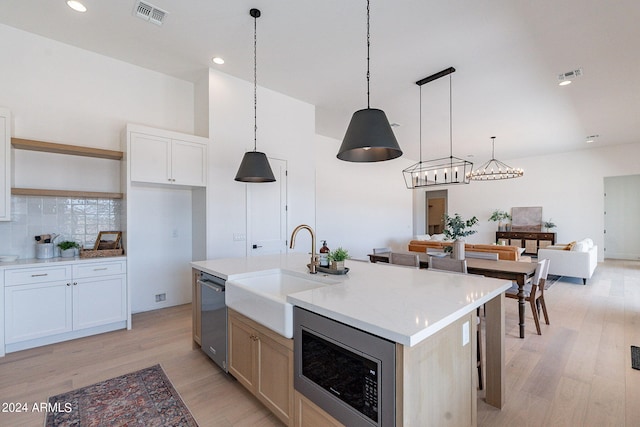 kitchen featuring light hardwood / wood-style flooring, tasteful backsplash, a kitchen island with sink, appliances with stainless steel finishes, and sink