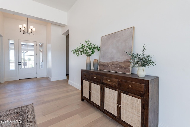 foyer featuring a towering ceiling, an inviting chandelier, and light wood-type flooring