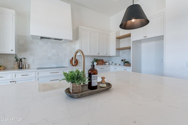 kitchen featuring backsplash, light stone countertops, white cabinetry, and pendant lighting