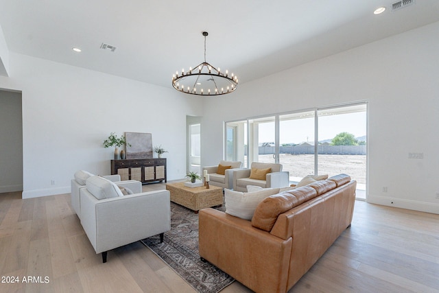 living room with an inviting chandelier, a water view, and light wood-type flooring