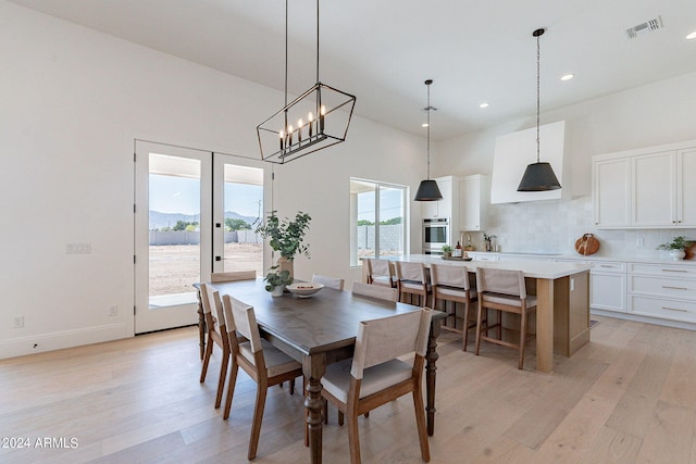 dining space featuring light hardwood / wood-style floors, french doors, and a chandelier