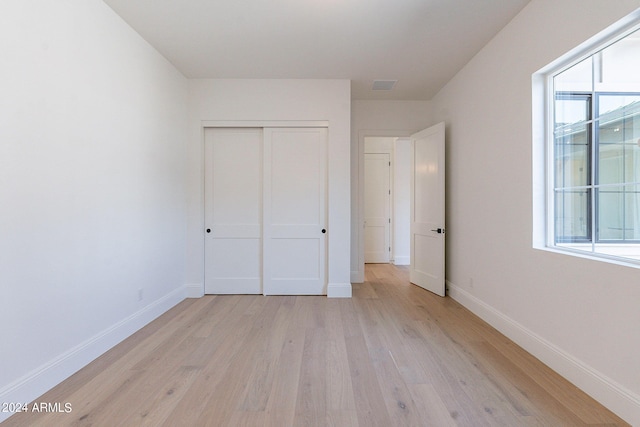 unfurnished bedroom with a closet and light hardwood / wood-style flooring