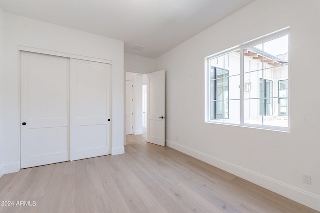 unfurnished bedroom with a closet and light hardwood / wood-style flooring