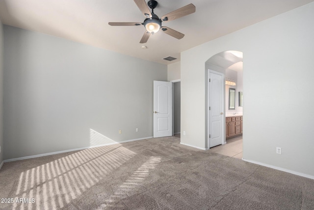 unfurnished bedroom featuring ensuite bathroom, light colored carpet, and ceiling fan