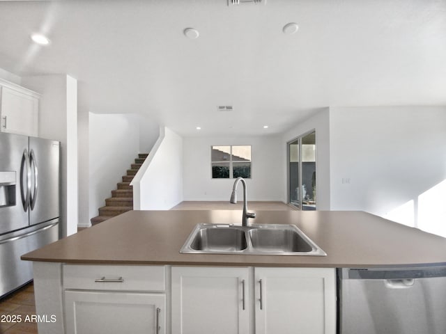 kitchen featuring an island with sink, appliances with stainless steel finishes, sink, and white cabinetry