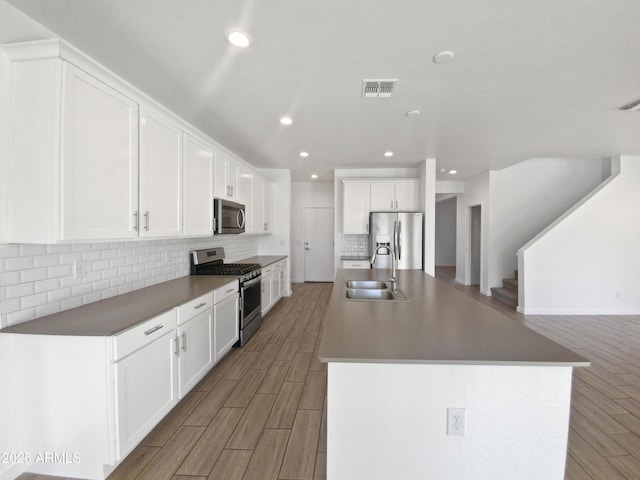 kitchen with backsplash, a center island with sink, sink, appliances with stainless steel finishes, and white cabinets