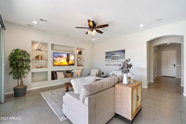 living room featuring ceiling fan, built in shelves, and tile patterned floors