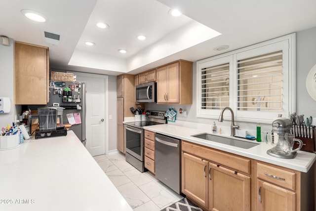 kitchen with a sink, light countertops, stainless steel appliances, a tray ceiling, and visible vents