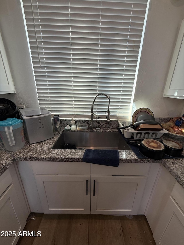 kitchen featuring sink, dark stone counters, dark hardwood / wood-style floors, and white cabinets