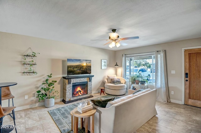 tiled living room with ceiling fan, a fireplace, and a textured ceiling