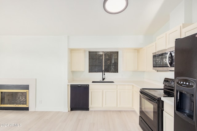 kitchen with light hardwood / wood-style floors, black appliances, and sink