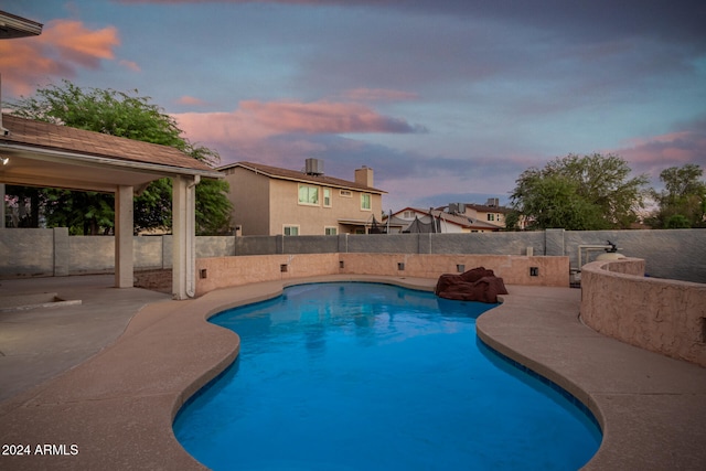 pool at dusk with a patio area