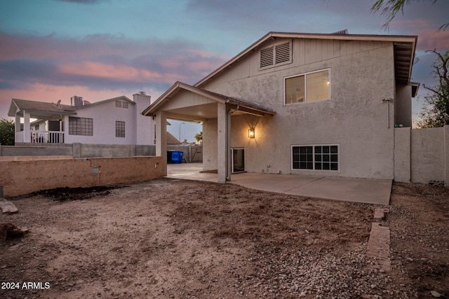 back house at dusk with a patio area