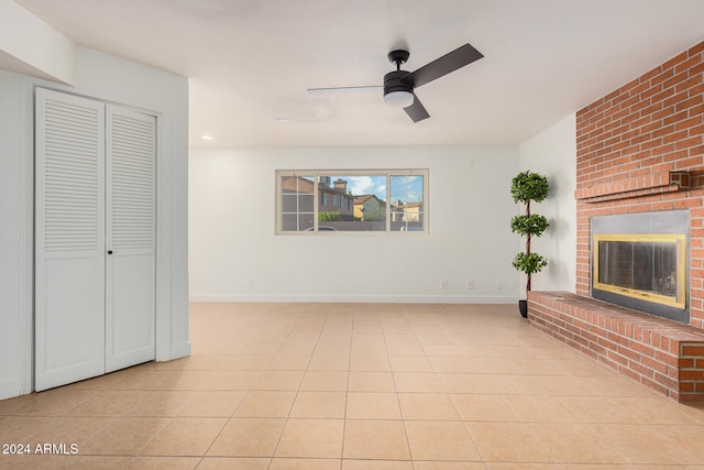 unfurnished living room with ceiling fan, light tile patterned floors, and a brick fireplace