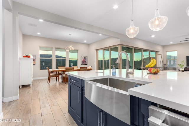 kitchen with blue cabinets, hanging light fixtures, a healthy amount of sunlight, and light wood-type flooring