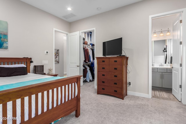 carpeted bedroom with ensuite bathroom, a closet, and a walk in closet