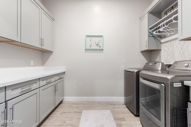 washroom with washer and clothes dryer, light wood-type flooring, and cabinets