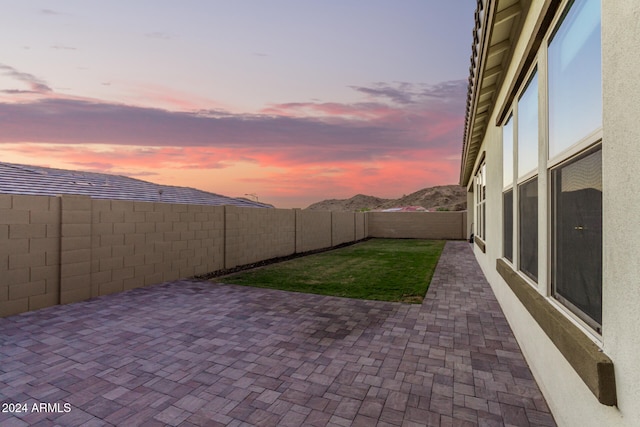 patio terrace at dusk featuring a lawn and a mountain view