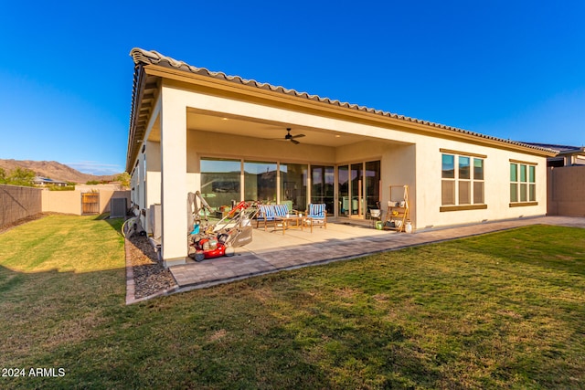 back of property with a patio area, a yard, a mountain view, and ceiling fan