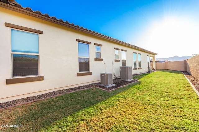 rear view of house with a lawn and cooling unit