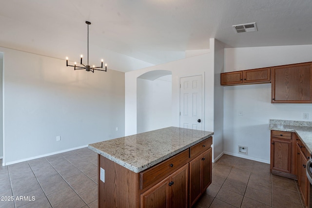 2518 W Carson Rd, Phoenix, AZ 85041 - kitchen featuring dark tile patterned flooring, arched walkways, brown cabinets, a chandelier, and decorative light fixtures
