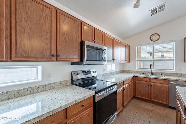 2518 W Carson Rd, Phoenix, AZ 85041 - kitchen with stainless steel appliances, a sink, vaulted ceiling, light tile patterned flooring, and brown cabinetry