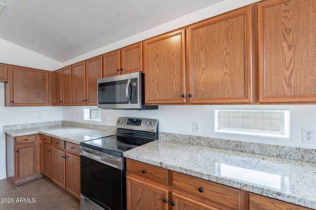 2518 W Carson Rd, Phoenix, AZ 85041 - kitchen featuring appliances with stainless steel finishes, vaulted ceiling, light tile patterned floors, light stone countertops, and brown cabinetry