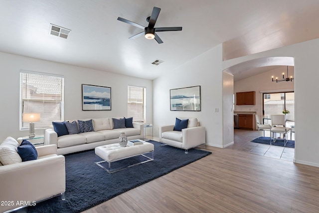 2518 W Carson Rd, Phoenix, AZ 85041 - living room featuring vaulted ceiling, arched walkways, a chandelier, a ceiling fan, and light wood finished floors