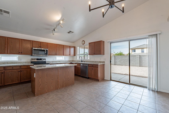 2518 W Carson Rd, Phoenix, AZ 85041 - kitchen with stainless steel appliances, a center island, brown cabinetry, track lighting, and light tile patterned floors