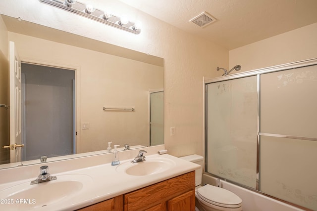 full bathroom featuring vanity, toilet, shower / bath combination with glass door, and a textured ceiling