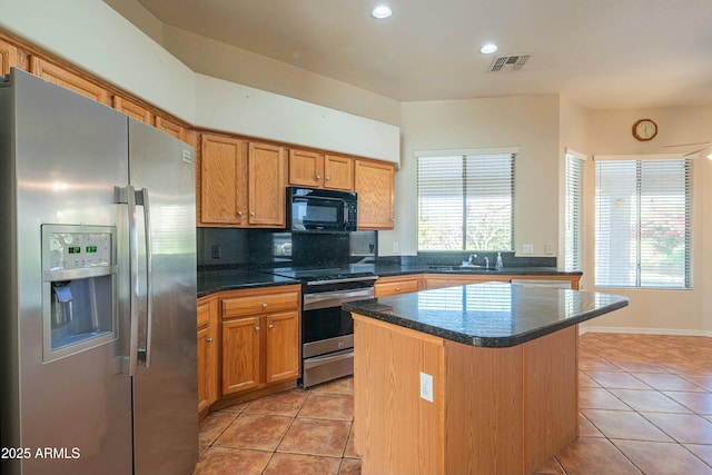 kitchen featuring decorative backsplash, a kitchen island, stainless steel appliances, and light tile patterned floors