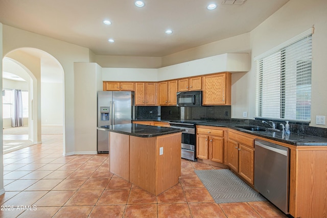 kitchen with sink, a center island, light tile patterned flooring, and appliances with stainless steel finishes