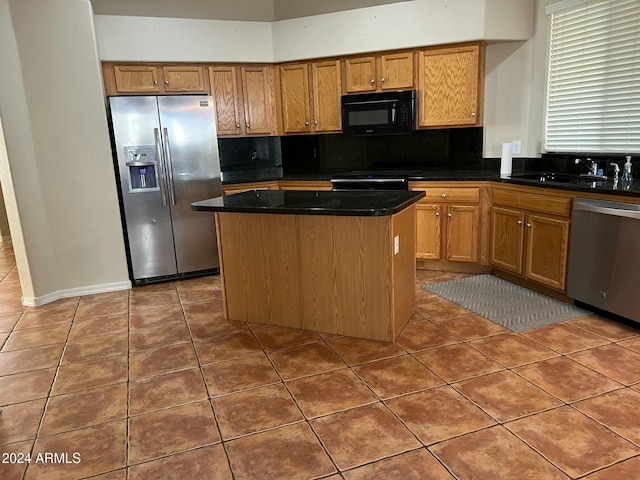 kitchen with sink, tile patterned flooring, dark stone countertops, a kitchen island, and stainless steel appliances