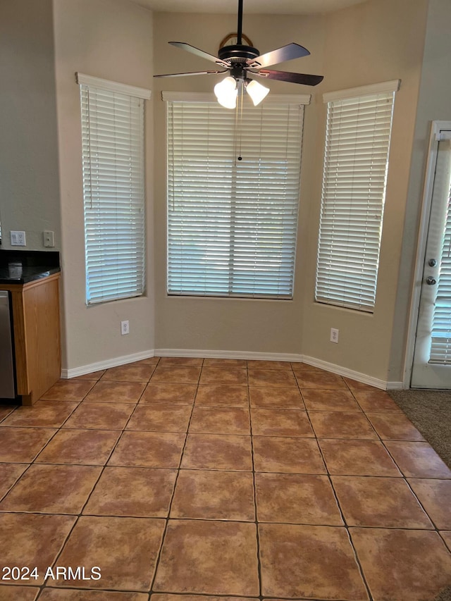 unfurnished dining area featuring tile patterned floors and ceiling fan