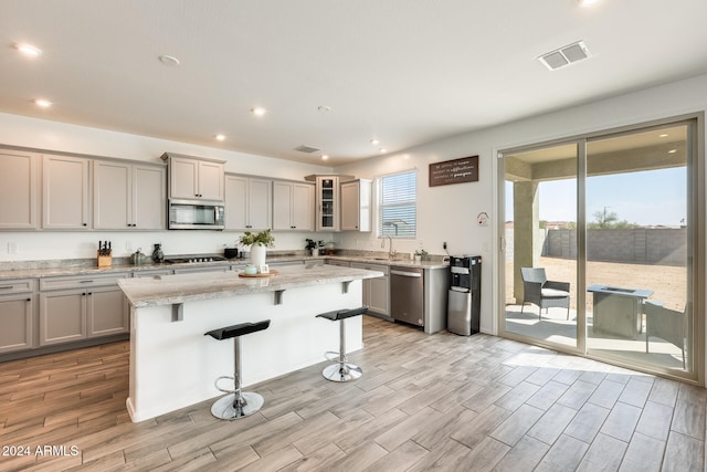 kitchen with light hardwood / wood-style flooring, a center island, stainless steel appliances, and a kitchen bar