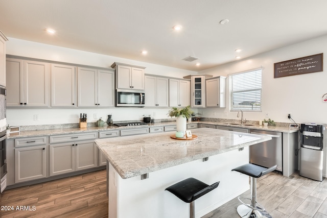 kitchen featuring a kitchen breakfast bar, light hardwood / wood-style flooring, stainless steel appliances, sink, and a center island