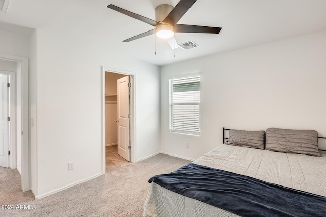 carpeted bedroom featuring a walk in closet, a closet, and ceiling fan