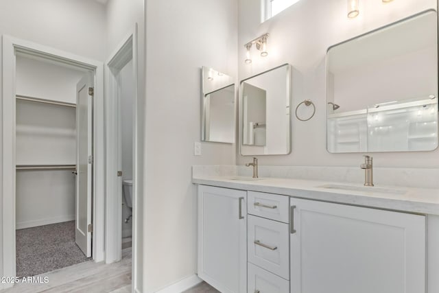 bathroom featuring a sink, toilet, a spacious closet, and double vanity