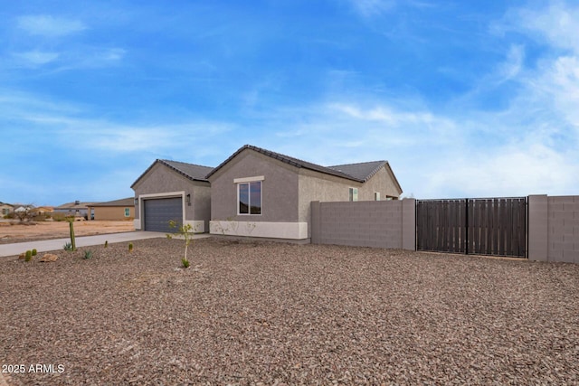 exterior space with stucco siding, driveway, a garage, and fence