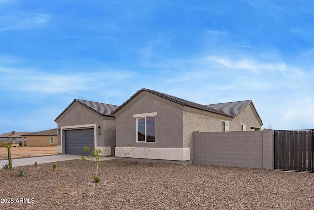 view of home's exterior featuring fence, stucco siding, concrete driveway, a garage, and a tile roof