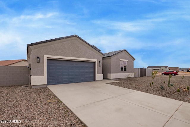 view of front of house with stucco siding, a garage, concrete driveway, and fence