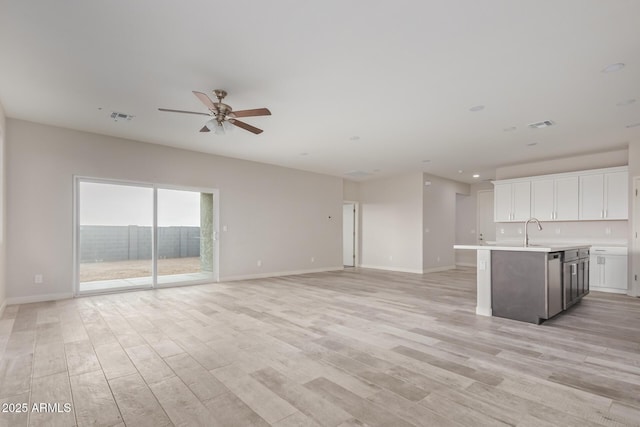 unfurnished living room featuring light wood-type flooring, visible vents, baseboards, and ceiling fan