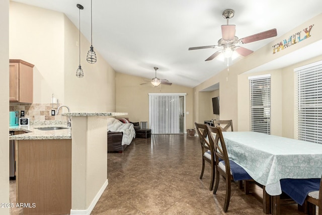 dining area featuring lofted ceiling, sink, and ceiling fan