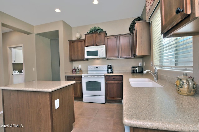 kitchen featuring light tile patterned floors, sink, white appliances, a center island, and independent washer and dryer