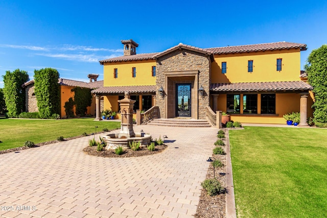 view of front of home with stone siding, stucco siding, a chimney, decorative driveway, and a front yard