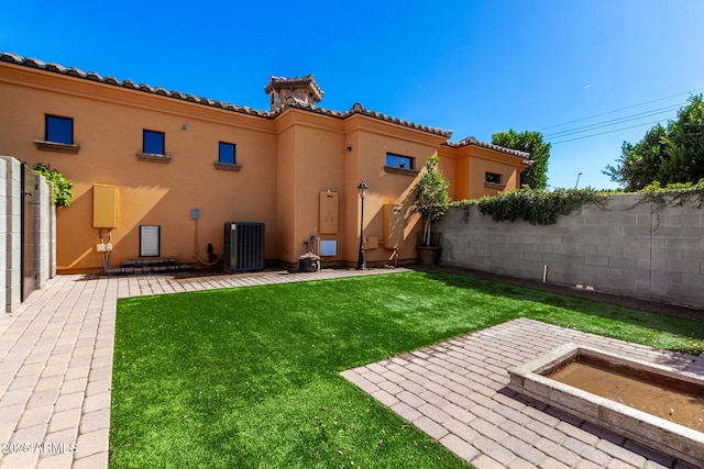 rear view of property with central air condition unit, stucco siding, a lawn, a patio area, and fence private yard